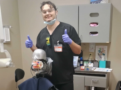 William Boardman giving thumbs up while practicing dental X-ray procedures on Dexter, a dental training mannequin at Denton DAS