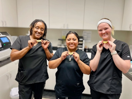 McKinney DAS students Kaisha, Abby, and Leslie smiling while holding their completed upper models for whitening trays