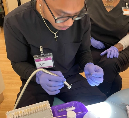  Close-up of a Pearland Dental Assistant student fine-tuning a temporary crown using dental tools 