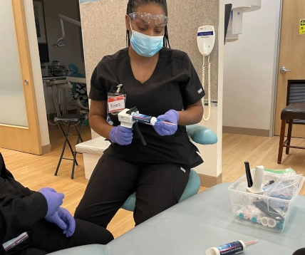  Two Pearland DAS students practicing temporary crown placement with instructor supervision 